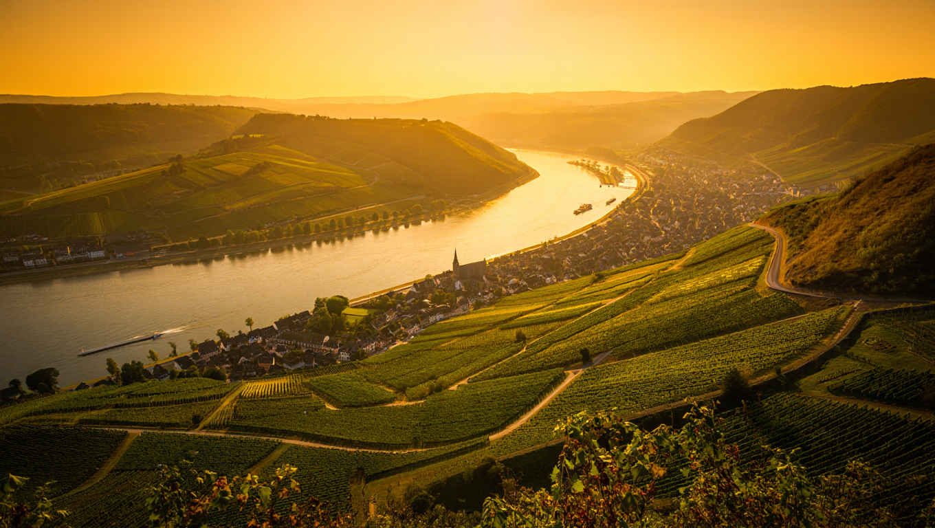 Panorama des Rheintals mit sanften Hügeln und glitscherndem Flusslauf bei Sonnenuntergang
